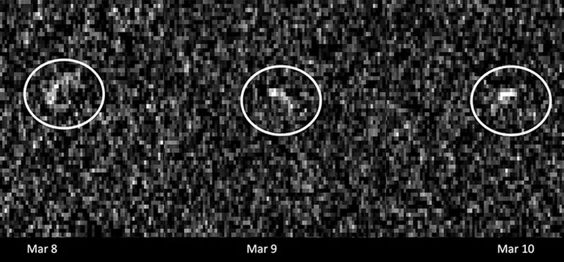 A white, grey, and black pixelated image, with three bright blobs spaced out across the center, and circled in white.